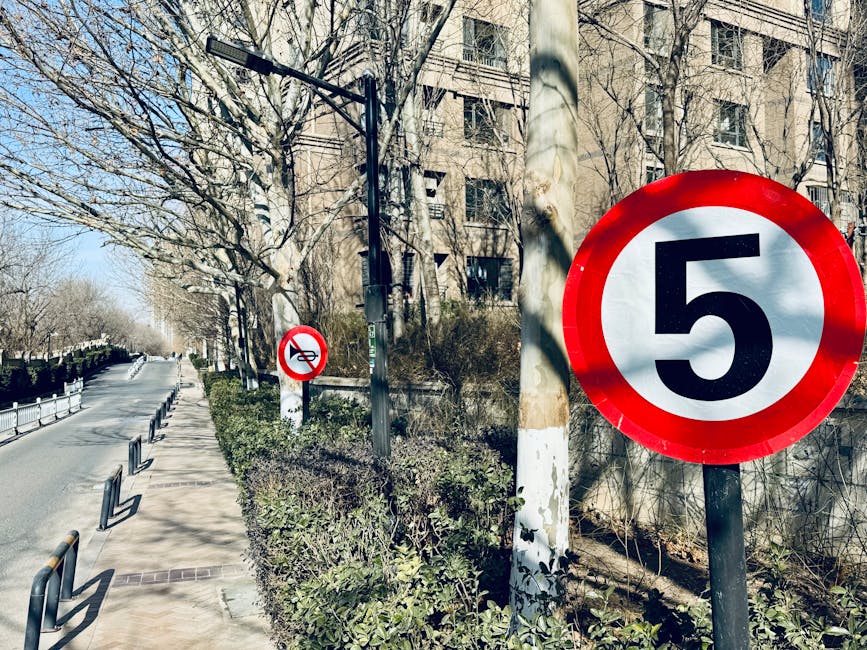 City sidewalk with speed limit and no motorcycles signs under clear blue sky.